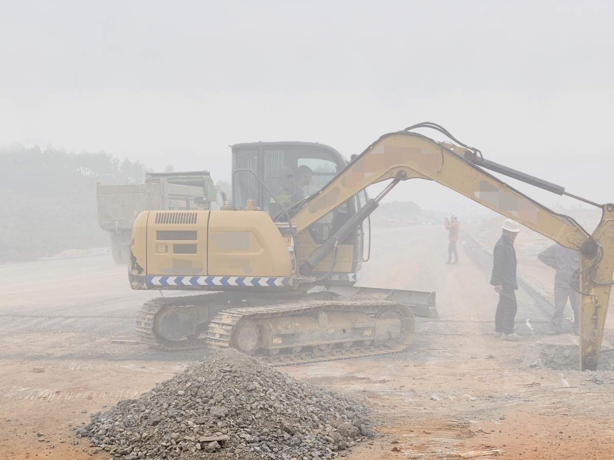 Excavator and workers in dense fog